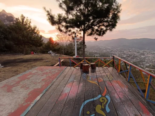 Cerro Kinich Ajaw Vista - Un mirador colorido con un árbol al centro y un diseño pintado en la plataforma, con vistas al valle